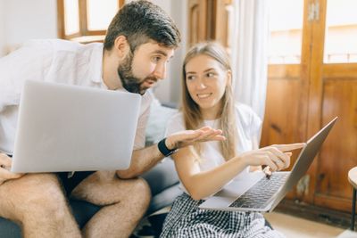A young couple reviewing their finances together on laptops at home