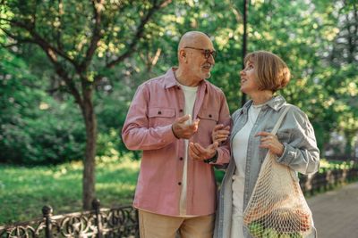 A retired couple walking and talking together in a park