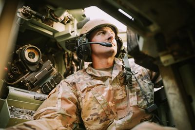 A U.S. Army servicemember seated at the controls inside an armored vehicle