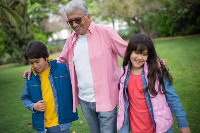 A grandfather walking outdoors with his two grandchildren