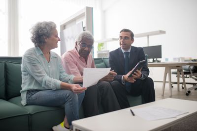 An advisor reviewing planning documents with a senior couple seated on a couch