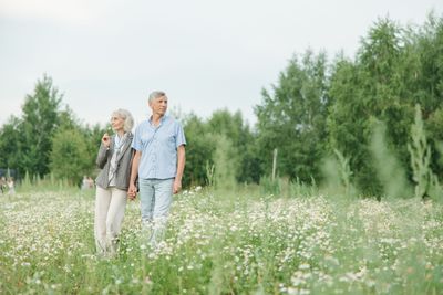 A mature couple walking together through a sunlit field of flowers