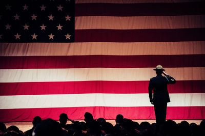 A uniformed service member saluting before a large American flag