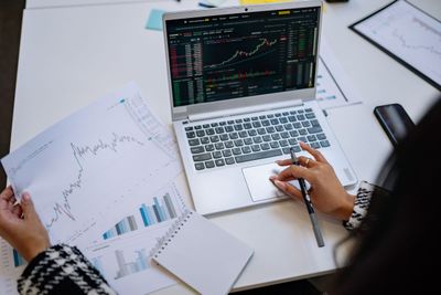Reviewing investment portfolio performance on a laptop alongside printed charts